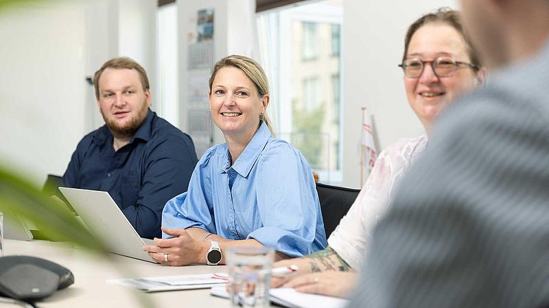 Two women and a man on a table in a meeting situation