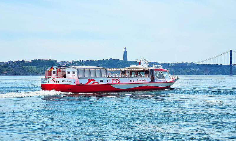 Vessel cruising on the Tagus river, Cristo Rei and the Ponte 25 de Abril in the background.
