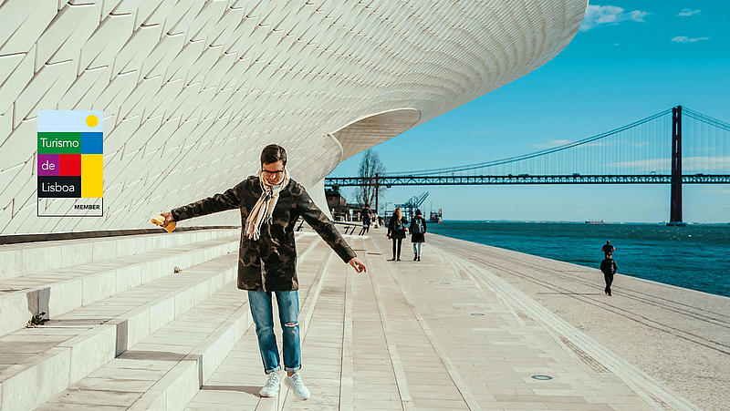 A man is balancing on a step next to the Museum of Art, Architecture and Technology.