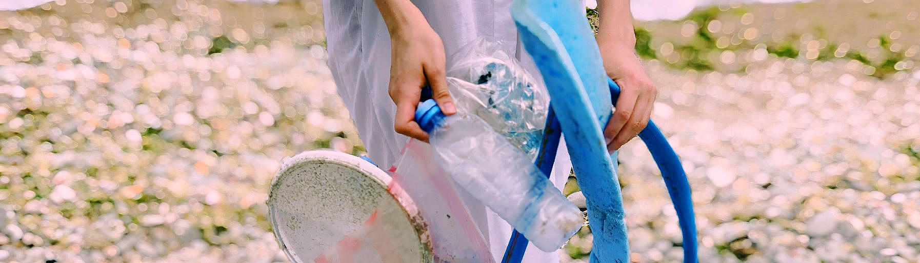 Picture of a woman cleaning up the beach.
