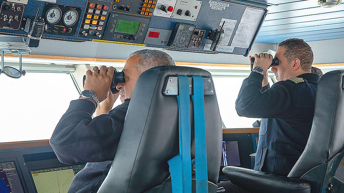 Two captains, who are looking through their binoculars.