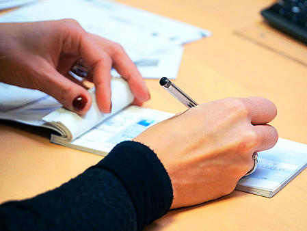 Picture of a person, who is signing a check.
