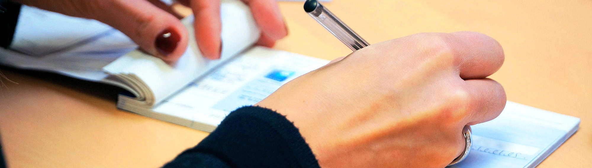 Picture of a person, who is signing a check.