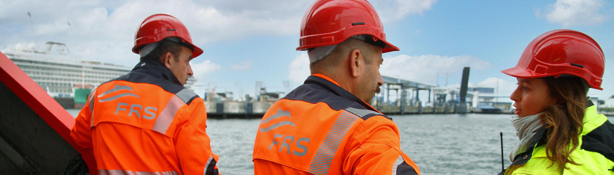 Crewmembers in safety clothing standing an a vessle