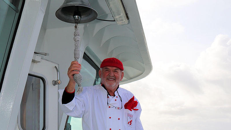 Der Koch von Gosch läutet eine Glocke.