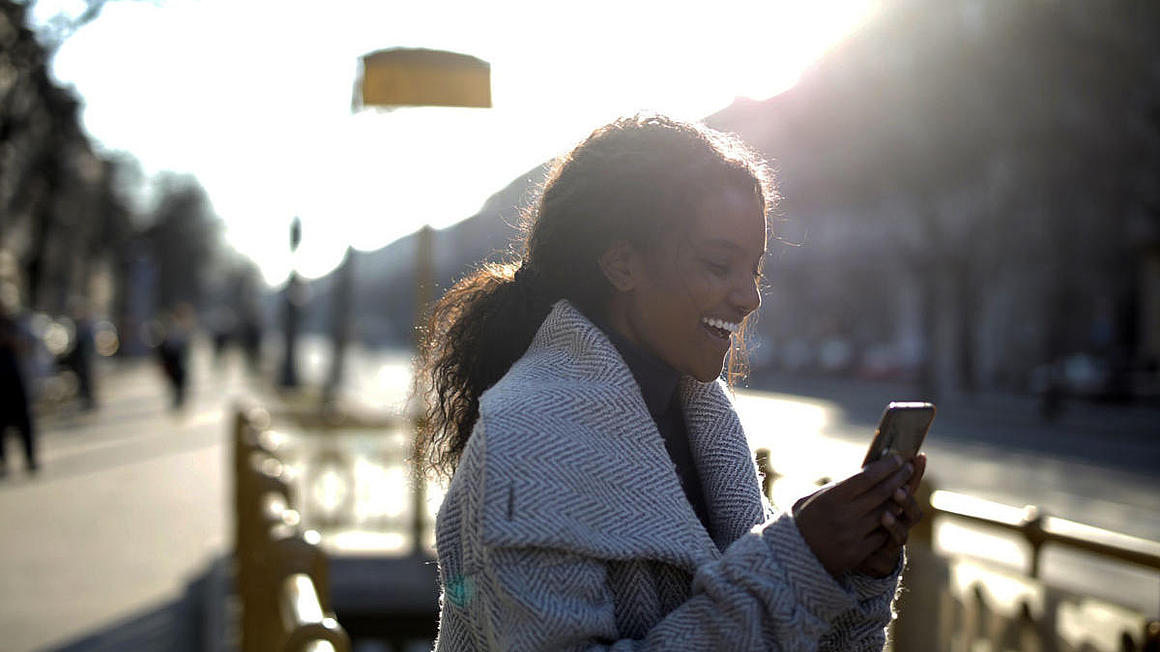 A woman holding her phone while laughing.