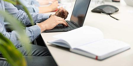 Man sitting on a table and writing on a notebook.