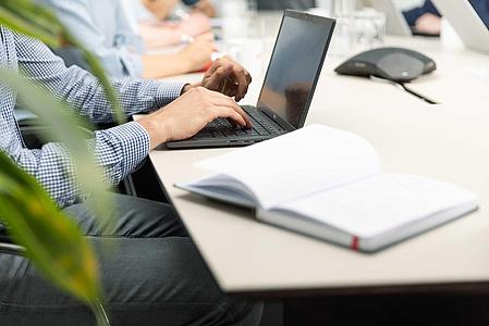 Man sitting on a table and writing on a notebook.