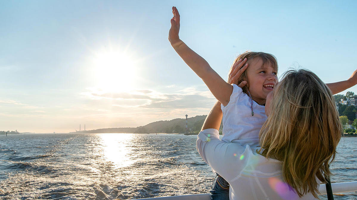 Mother lifting her daughter at the ship's railing.